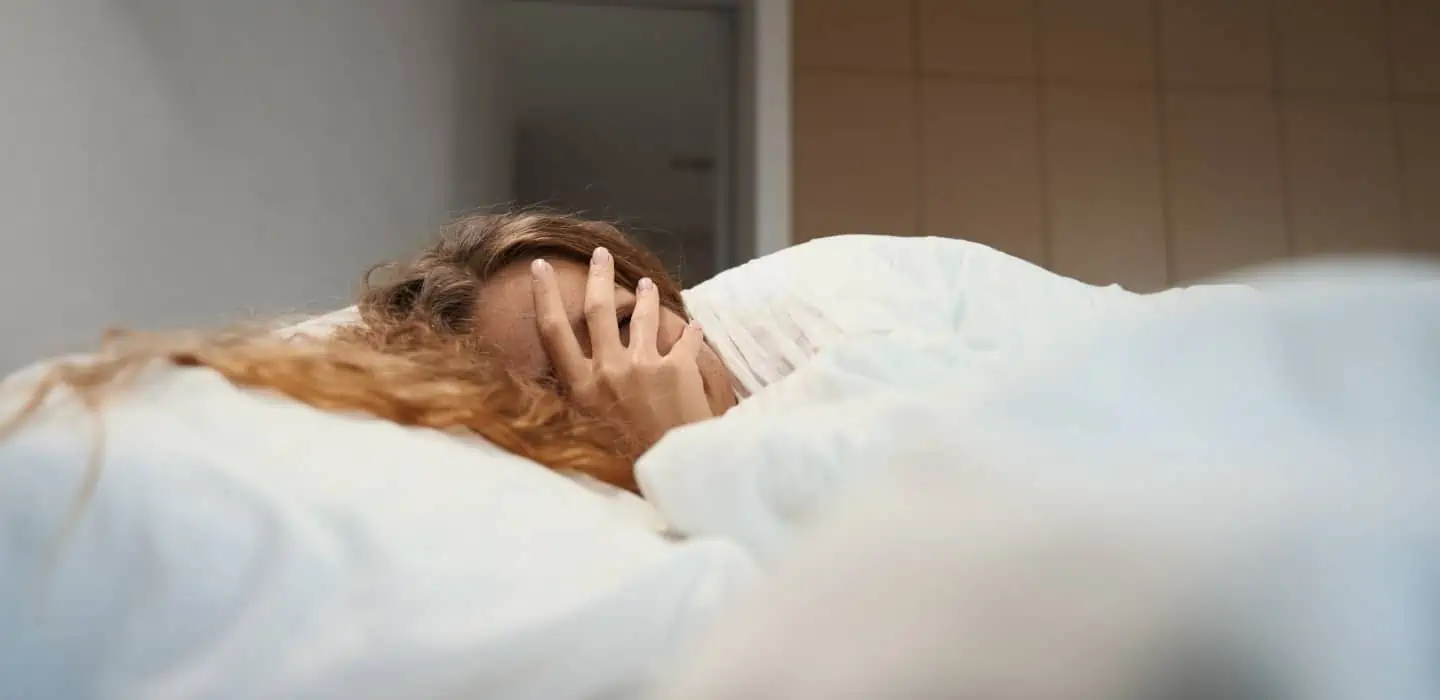 Frau liegt im Bett und ist gerade aufgewacht von Ihrem Traum, wo ihr die Zähne ausgefallen sind